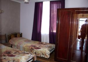 a room with two beds and a cabinet and a window at Armen's Guest House in Tatʼev