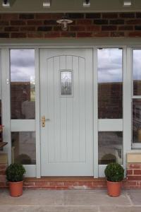 a white front door of a house with two plants at The Annex at Oliver Farm in York