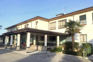 un grand bâtiment blanc avec un palmier en face dans l'établissement Hotel Internazionale Gorizia, à Gorizia