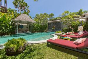 a backyard with a pool with red furniture and a gazebo at Villa Sky Li by Nagisa Bali in Seminyak