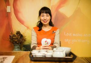 a woman standing at a table with a tray of dishes at Lydia Craft Guesthouse in Seoul