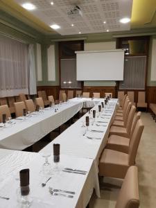 a conference room with tables and chairs and a white screen at Hôtel de l'Europe in Saint-Jean-de-Maurienne