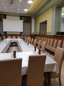 sala konferencyjna ze stołami i krzesłami oraz białym ekranem projekcyjnym w obiekcie Hôtel de l'Europe w mieście Saint-Jean-de-Maurienne
