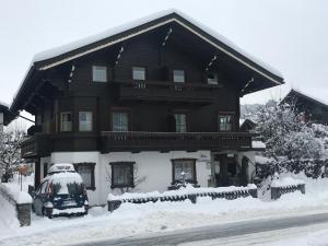 een besneeuwd huis met een auto ervoor geparkeerd bij Pension Kuntschner in Mittersill