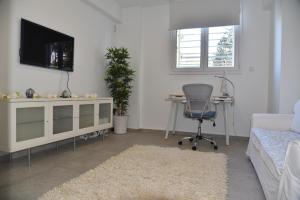 a living room with a tv and a desk and a chair at Acropolis At Your Door in Athens