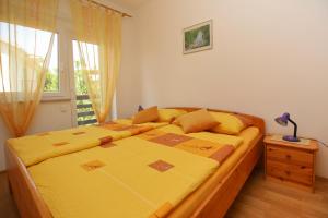 a bedroom with a bed with yellow sheets and a window at Apartments Nikolic in Šilo