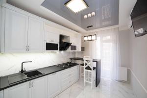 リヴィウにあるLEOGRAND Apartments on Kulisha 36のキッチン(白いキャビネット、黒いカウンタートップ付)