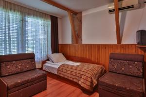 a bedroom with a bed and a chair and a tv at Guest House Villa Teres in Shipka
