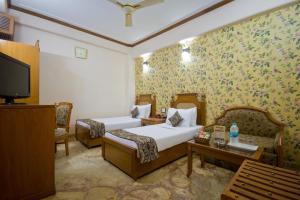a hotel room with two beds and a tv at Hotel Sunstar Grand in New Delhi