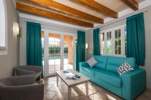 Una sala de estar con un sofá azul y sillas. en Villas Maribel, en Cala Blanca