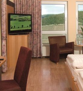 ein Hotelzimmer mit einem Bett, einem TV, einem Bett und einem Fenster in der Unterkunft Burg-Hotel in Obermoschel
