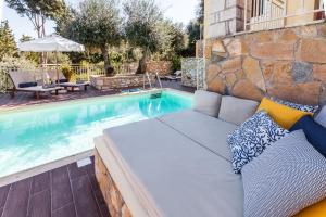 a swimming pool with a couchitures next to a swimming pool at Villas Muscalas by Konnect, 200m from the Beach in Lákka
