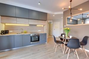 a kitchen with blue cabinets and a table and chairs at Apartamenty Chmielna 72 in Gdańsk