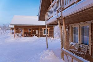 a log cabin in the snow with two chairs in front at Saivaara Cottages in Kilpisj&auml;rvi