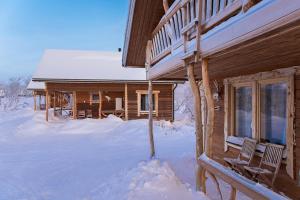 a log cabin in the snow with two chairs in front at Saivaara Cottages in Kilpisjärvi