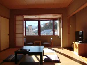 a living room with a table and a window at Hakuba Hotel Ougiya in Hakuba