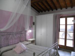 サン・クイーリコ・ドルチャにあるAntico Podere la Martinellaのベッドルーム1室(ピンクの天蓋付きベッド1台付)