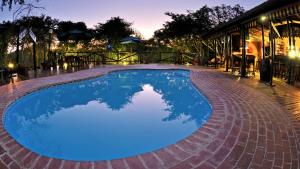 a large blue swimming pool with a brick patio at Isinkwe Bush Camp in Hluhluwe
