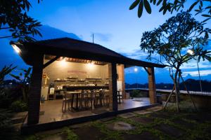 a pavilion with tables and chairs on a deck at night at Grandpa Guest House in Canggu