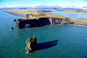 a large rock formation in the water near a beach at Hótel Kría in Vík
