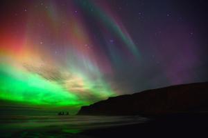 a group of people standing under the northern lights at Hótel Kría in Vík