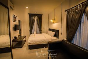 - une chambre avec un lit, un canapé et un miroir dans l'établissement The Warehouse Chiang Mai, à Chiang Mai