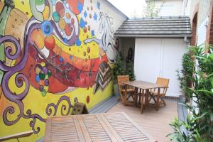 une fresque murale sur le côté d'une maison avec une table et des chaises dans l'établissement Chambre D'hôtes Les Epicuriens, à Épernay