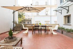 eine Terrasse mit einem Tisch, Stühlen und einem Sonnenschirm in der Unterkunft Mami's Home Trastevere apt with private terrace in Rom
