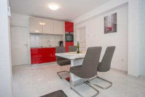 kuchnia z czerwonymi szafkami oraz białym stołem i krzesłami w obiekcie Apartment Aldo II w Poreču