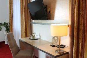a hotel room with a desk with a tv on a wall at Hotel 3 Linden in Leipzig