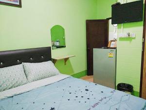 a bedroom with a bed and a small refrigerator at Your Home in Chiang Rai