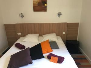 a bed with three pillows on top of it at Kyriad Direct Agen in Castelculier