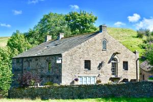 an old stone church with a hill in the background at Low Mill Guesthouse in Bainbridge