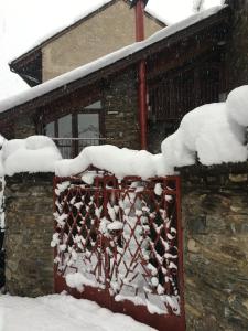 una cerca cubierta de nieve frente a una casa en La Llúpia en Isavarre