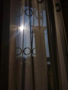 una ventana con una cortina con el sol brillando en Piccolo Mondo, en Zovencedo