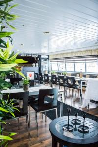 a dining room with tables and chairs and plants at Hotellilaiva Wuoksi in Kuopio