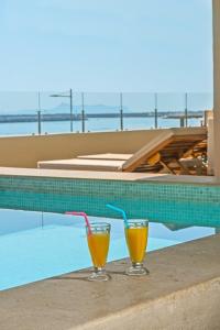 two glasses of orange juice sitting on a table next to a swimming pool at Swell Boutique Hotel in Rethymno Town