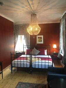 1 dormitorio con 2 camas y lámpara de araña en Sogndalstrand Kulturhotell en Sogndalsstrand