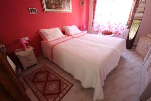 a bedroom with a white bed in a red room at beb "Ziu Antoi e Zia Srivia" in Sestu