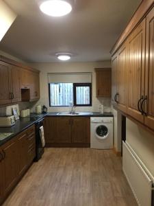 a kitchen with wooden cabinets and a washing machine at fairhill holiday let in Ballycastle