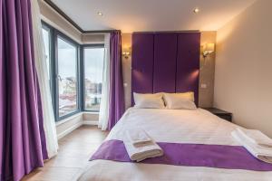 a bedroom with a large bed with a purple headboard at The Embassy Nord in Bucharest