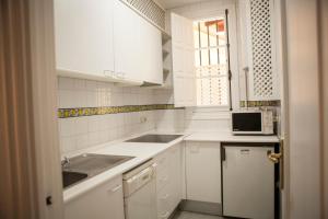 a white kitchen with a sink and a microwave at CATEDRAL, GRAN PATIO, PLENO CENTRO in Seville