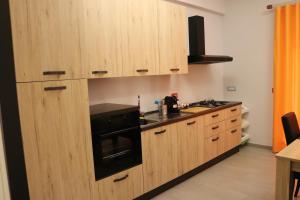 una cucina con armadi in legno e forno a piano cottura nero di Vista Reale Apartment a Caserta