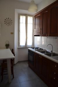 eine Küche mit Holzschränken, einem Waschbecken und einem Fenster in der Unterkunft Holidayhouse Ostia - Maestrale in Lido di Ostia