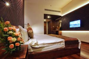 a hotel room with a bed and flowers on a table at Woodies Bleisure Hotel in Kozhikode