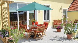 einen Tisch und Stühle unter einem Sonnenschirm auf einer Terrasse in der Unterkunft Ferienbauernhof Herrmann in Herrieden