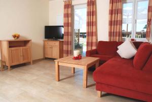 a living room with a red couch and a tv at Ferienbauernhof Herrmann in Herrieden