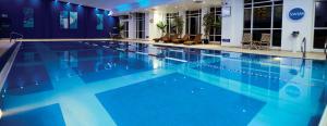 a large swimming pool with blue water in a building at The Lodge At Meyrick Park in Bournemouth