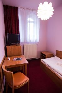 um pequeno quarto com uma cama, uma secretária e uma mesa em Hotel Hron em Náchod