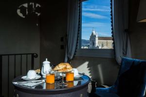 فندق بالاتزو روزيللي كيكوني في فلورنسا: طاولة مع طبق من الطعام وعصير البرتقال